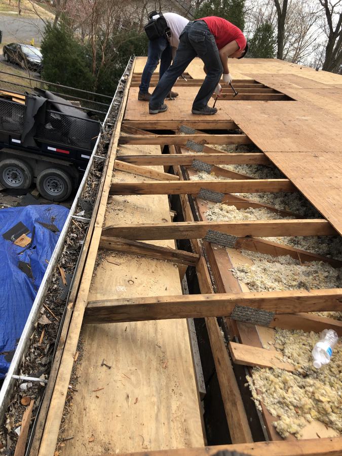 Crew replacing roof decking along the full length of a house